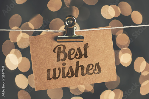 Best wishes sign pegged to a string with blurred bokeh lights in the background