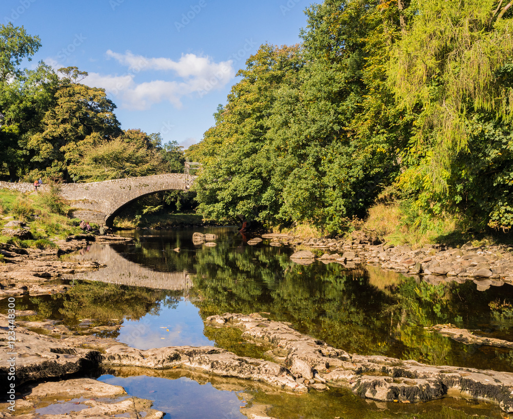 Obraz premium The river Ribble at Stainforth bridge in early Autumn sunshine, Stainforth, Settle, North Yorkshire, UK