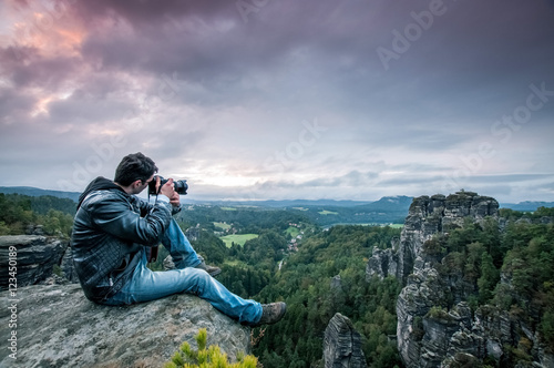 Mann sitzt auf den Berg und macht ein Foto photo