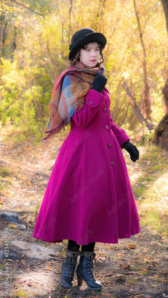 girl in a bright crimson coat walking in forest sunny autumn day