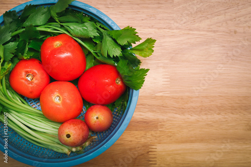 fresh tomatoes and vegetable in a basket on wooden background. top view.