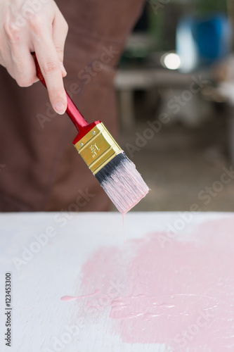Close up paintbrush in hand and painting on the wooden table,Retro and vintage style,A woman holding brush and painting on the wooden table,