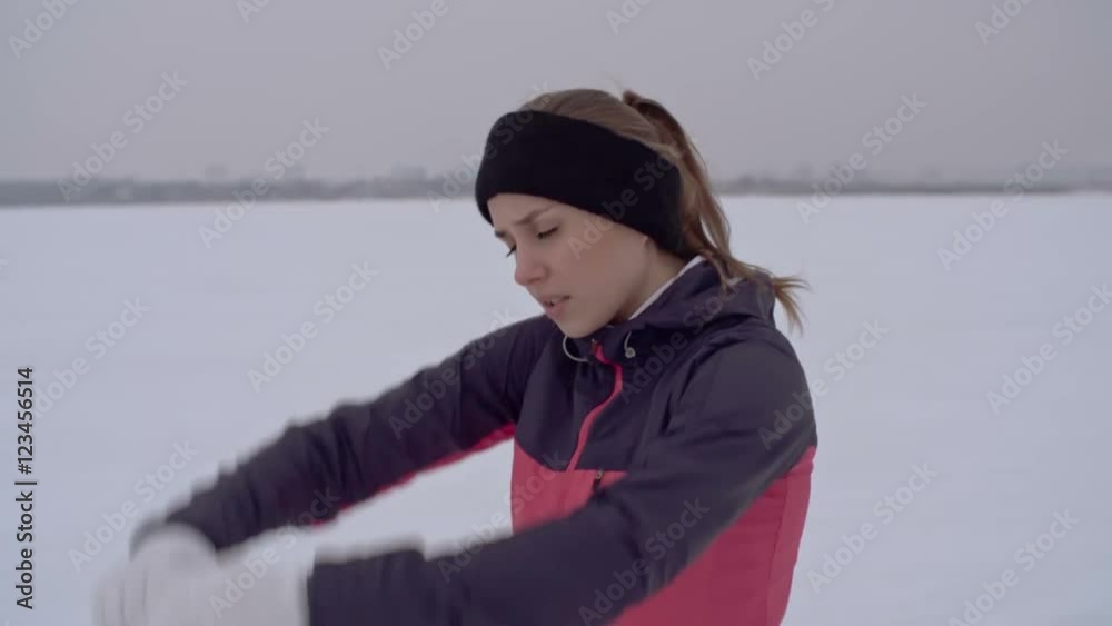 MS Young woman doing warm-up exercises before jogging in snow