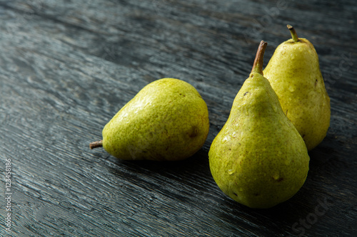Slika na platnu Three green pear on a black background