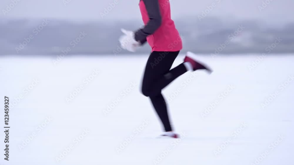 Tracking shot of young athletic woman practicing winter running in snow Tracking shot of young athletic woman practicing winter running in snow
