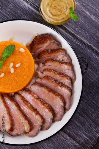 Roast duck breast and pumpkin mash, served with mint and pine nuts. Slices of duck with sweet butter squash, mustard and honey sauce. View From Above, Top Studio Shot