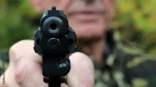 Man with black gun. Retired officer in military uniform at shooting range. Man holds in hands black revolver photo