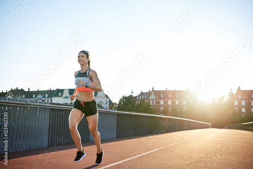 Cheerful woman running along city bridge