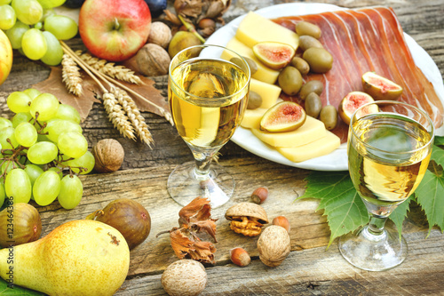 White wine, prosciutto, cheese and seasonal fruits on rustic table - (Delicious Mediterranean meal) 