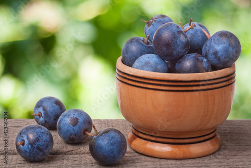 blackthorn berries in a wooden bowl on table with sacking and blurred background