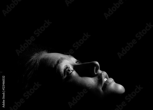 face of girl looks up in dark monochrome image