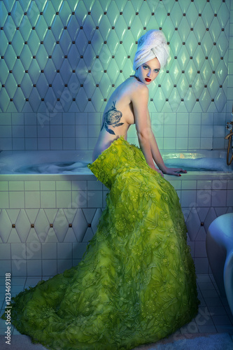 Woman in green skirt sitting on bath with tattooed back  (ID: 123469318)