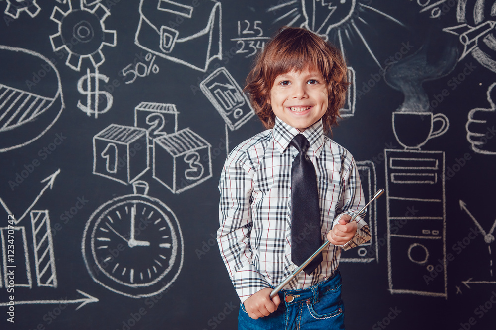 Little boy as a businessman or teacher standing and holding pointer on dark background with business school picture