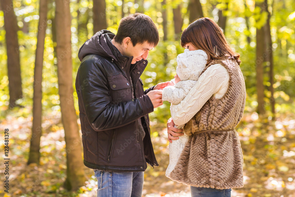 Fototapeta premium young family with their newborn baby spending time outdoor in the autumn park.