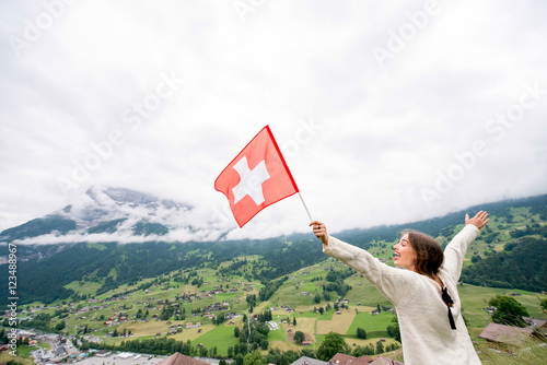 Young woman with swiss flag enjoying great view on the mountains. Having happy vacations in Switzerland photo