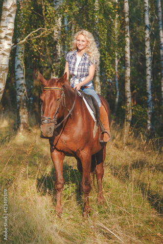 Beautiful young woman riding a horse © vladdeep