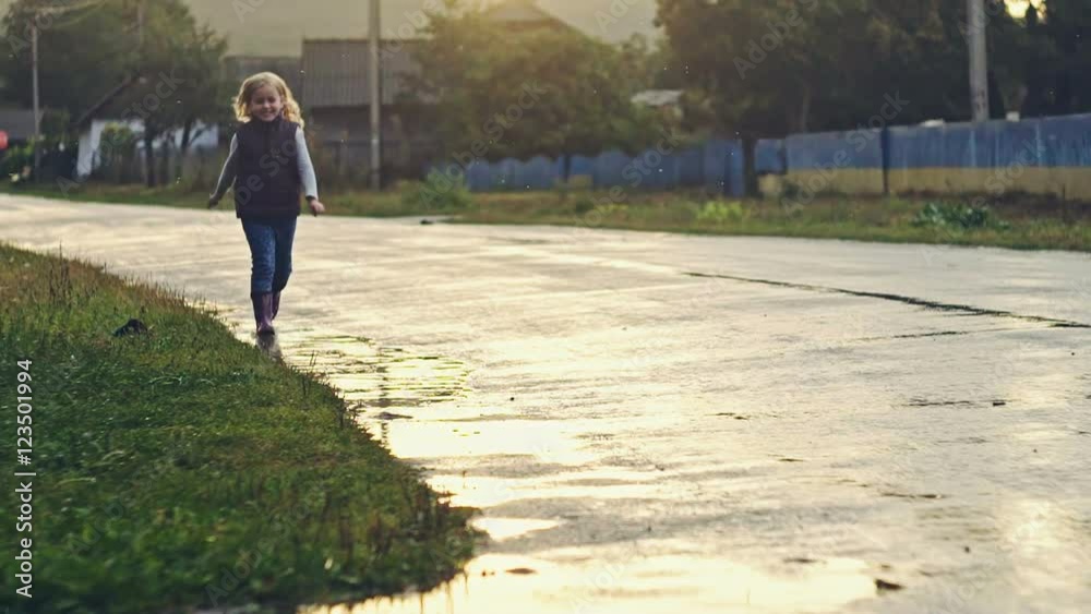 Happy child girl running and puddles in the rain in summer Happy child girl running and puddles in the rain in summer