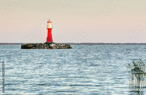 Red lighthouse in the water during sunset. Pervalka village, Lithuania.
