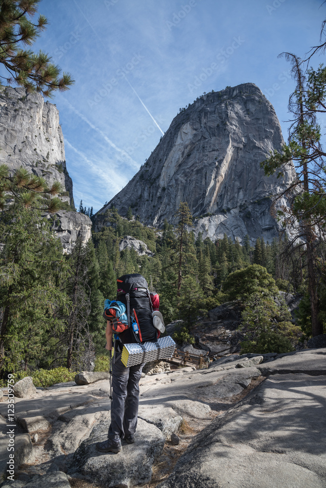 hiker standign in front of liberty cap of Yosemite
