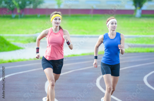 Jogging and Fitness Concepts. Two Young Caucasian Athletes Running On Stadium