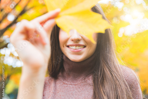 Canvas Print Smiling woman portrait with a yellow leaf in autumn