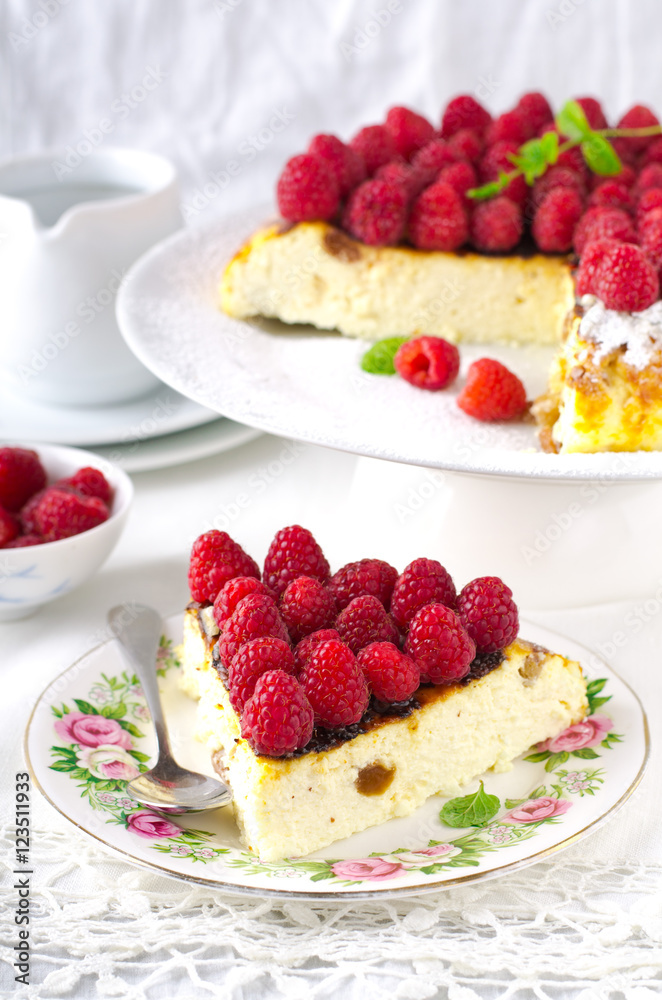 Cheesecake, souffle, cream mousse, pudding dessert with fresh raspberries and mint leaves on a white plate Cheesecake, souffle, cream mousse, pudding dessert with fresh raspberries and mint leaves on a white plate