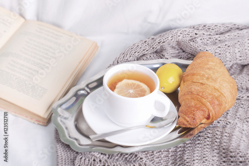breakfast cup of tea with croissant on a blanket in the bed.toned foto
