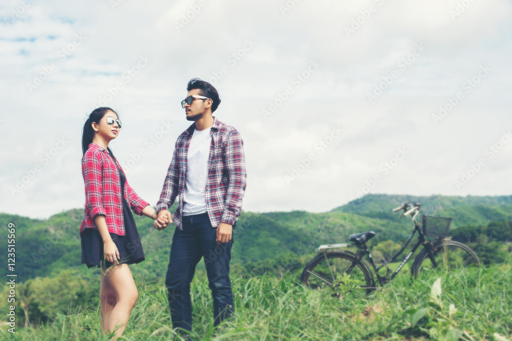 Young hipster couple holding hands walking on the meadow relaxin