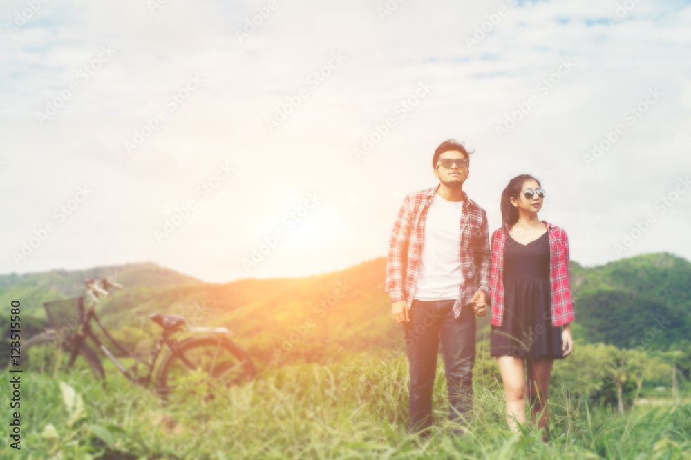 Young hipster couple holding hands walking on the meadow relaxin Young hipster couple holding hands walking on the meadow relaxin