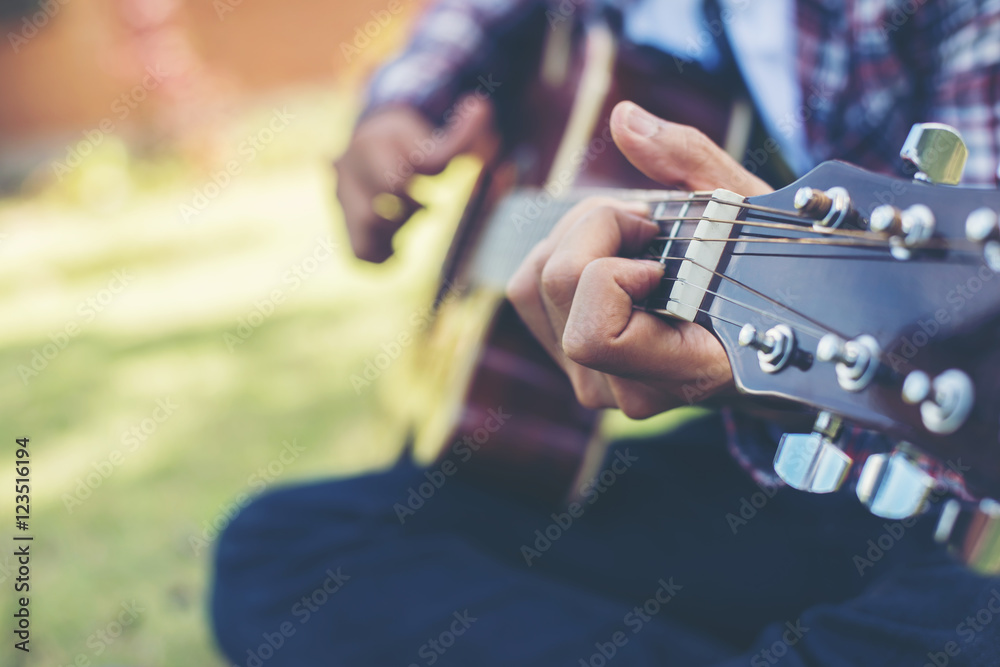Close up of young hipster man practiced guitar in the park,happy