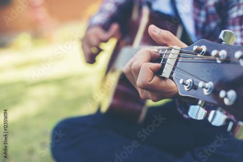 Close up of young hipster man practiced guitar in the park happy