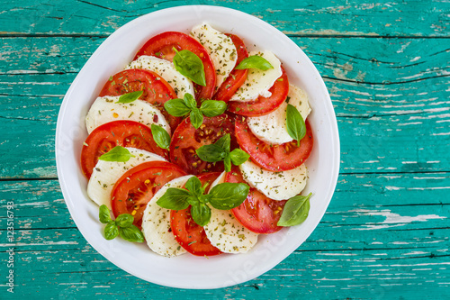 Delicious caprese salad with ripe tomatoes and mozzarella cheese with fresh basil leaves. Italian food. 