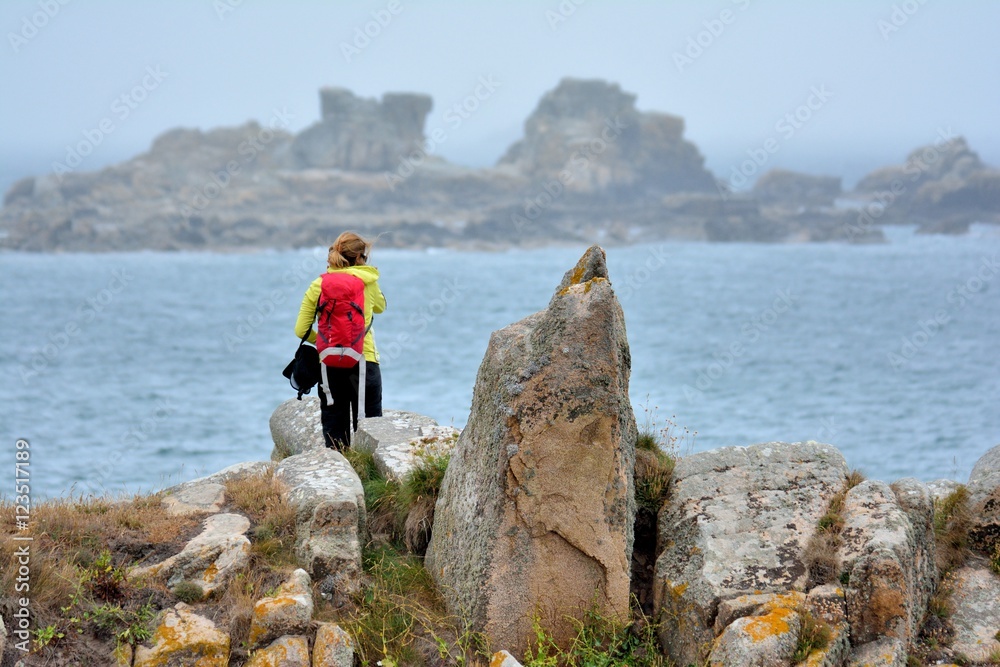 Une jeune randonneuse prend des photos de la côte et la mer à Plougrescant en Bretagne