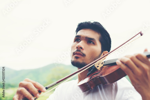 Young hipster musician man play violin in the nature outdoor lif
