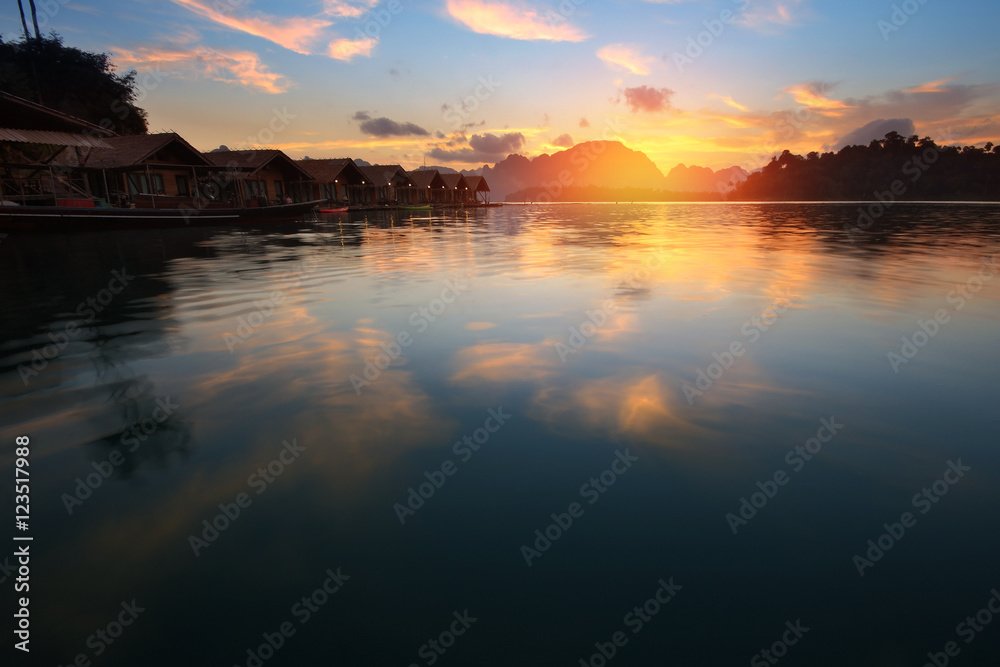 Silhouette scenery during sunrise of houseboat resort at lake river in natural attractions,Ratchaprapha Dam at Khao Sok National Park,Surat Thani Province in Thailand.Traveling , recreation Concept