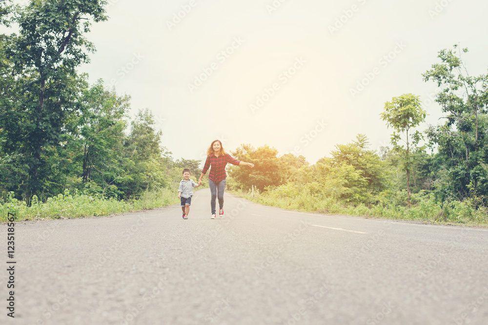 Little boy holding his mother hand running on the street enjoy g