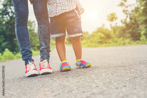 Mother is walking on the road with her little baby boy son feet