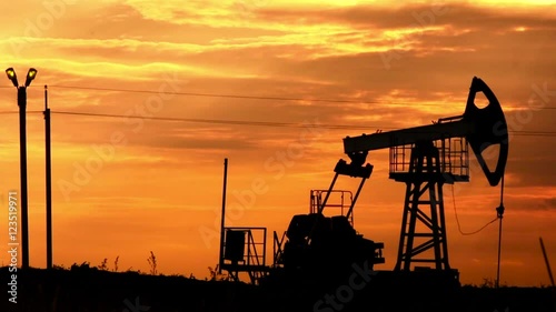 Silhouette of oil pumpjack at sunset. Oil and gas industry equipment. photo