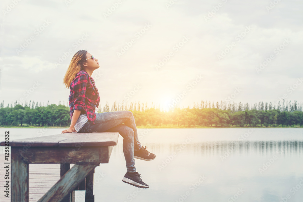 Young beautiful hipster woman sitting on the lake pier ,Relaxed