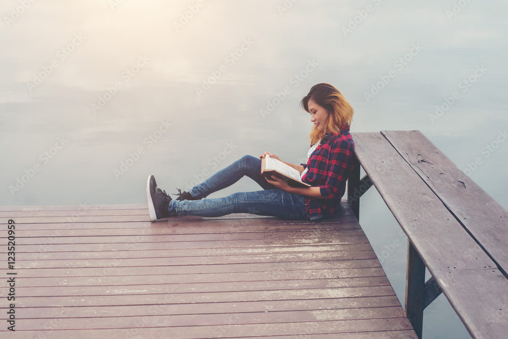 young beautiful hipster woman relaxing sitting on pier reading b