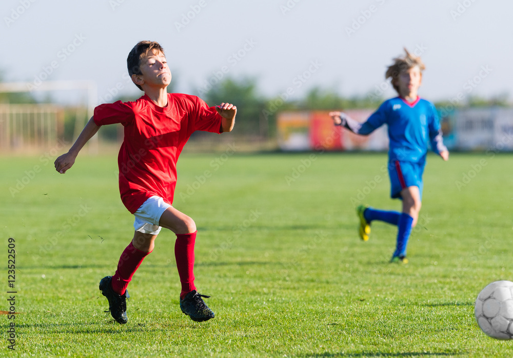 Boys playing football soccer game on sports field Boys playing football soccer game on sports field