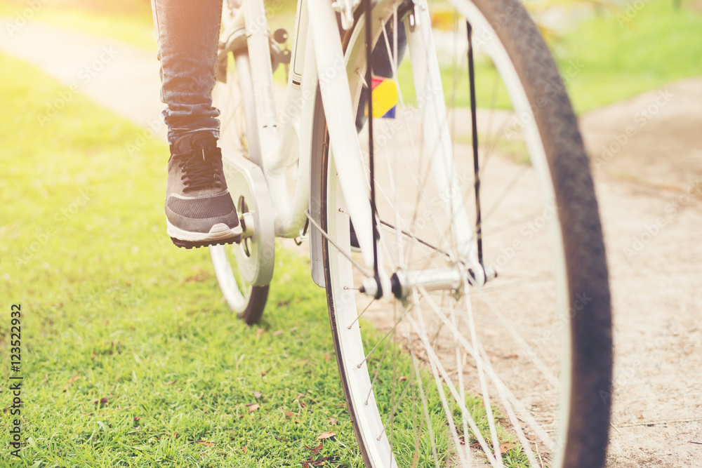 Fototapeta premium Close-up of young hipster woman holding her foot on bicycle peda