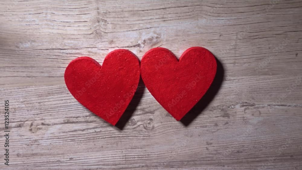 Young woman placing two red hearts on a wooden table, top view. Romance, love, Valentine's day, relationship concepts. 4K video Young woman placing two red hearts on a wooden table, top view. Romance, love, Valentine's day, relationship concepts. 4K video