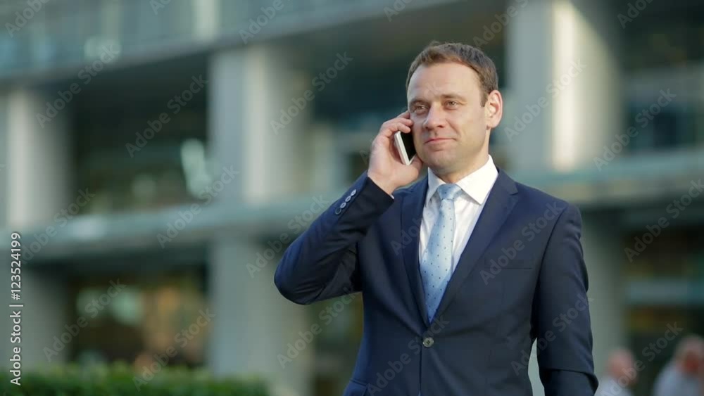Attractive businessman talking on the phone in city Attractive businessman talking on the phone in city