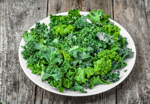 Preparing kale chips from green leaves chopped on white plate