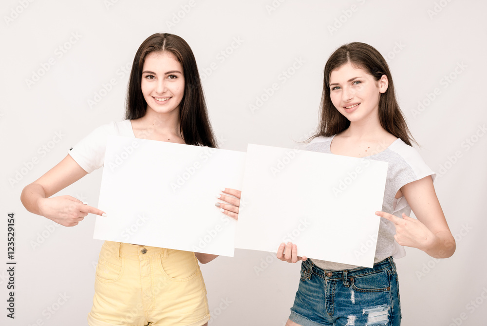 Two happy smiling young women carring big blank signboard Two happy smiling young women carring big blank signboard