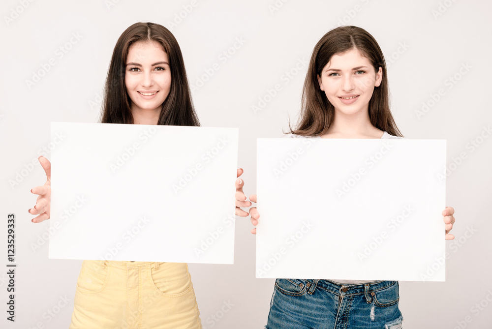Two happy smiling young women carring big blank signboard Two happy smiling young women carring big blank signboard
