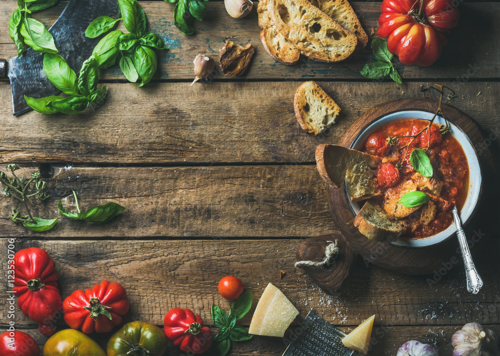 Homemade Italian roasted tomato and garlic soup in bowl with basil and Parmesan cheese over old rustic wood background with copy space in center, top view, horizontal composition Homemade Italian roasted tomato and garlic soup in bowl with basil and Parmesan cheese over old rustic wood background with copy space in center, top view, horizontal composition