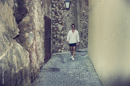 Stylish man walking in old city towards camera 
