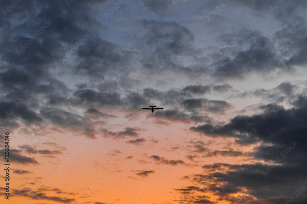 Airplane in the air and sunset sky in background